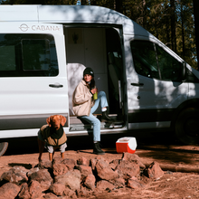 Lade das Bild in den Galerie-Viewer, Playmate Elite 6L Kühlbox. praktisch. Perfekt für Camping und Caravaning. Farbe: Rot. Igloo. Lifestylebild im Wald am Caravan mit Hund