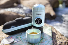 Load image into Gallery viewer, camping espressomaschine. Nanopresso Arctic Blue. Leicht zu bedienen. Espresso überall genießen. Farbe: Hell Blau. Wacaco. Lifestyle bild auf Stein