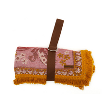 Load image into Gallery viewer, Wandering Folk Woven Throw Rosé | Boho ; Farbe: Rosa, Ockergelb ; mit Fransen ; Blumenmuster ; Produktfoto zusammengerollte Decke mit Träger  ; Campingdecke